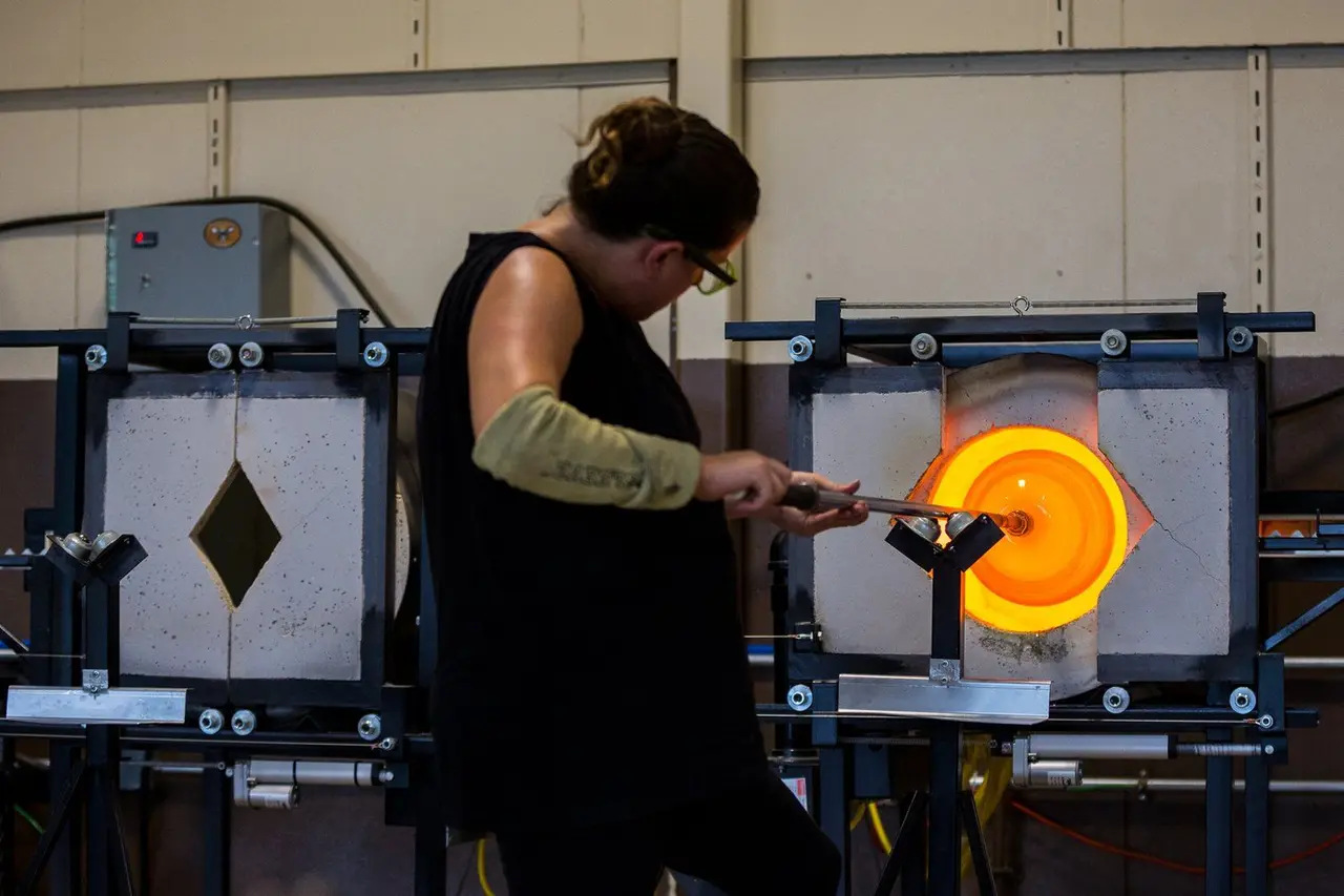 A glassblower turns a piece at the glory hole