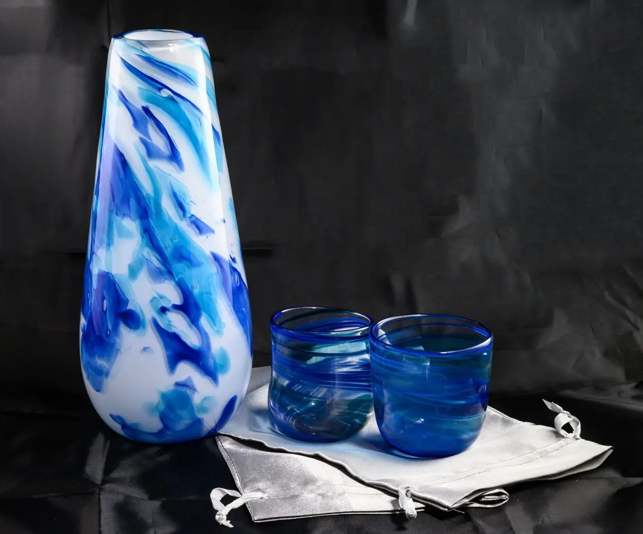 A blue and white swirled vase beside two blue chuppah glasses
