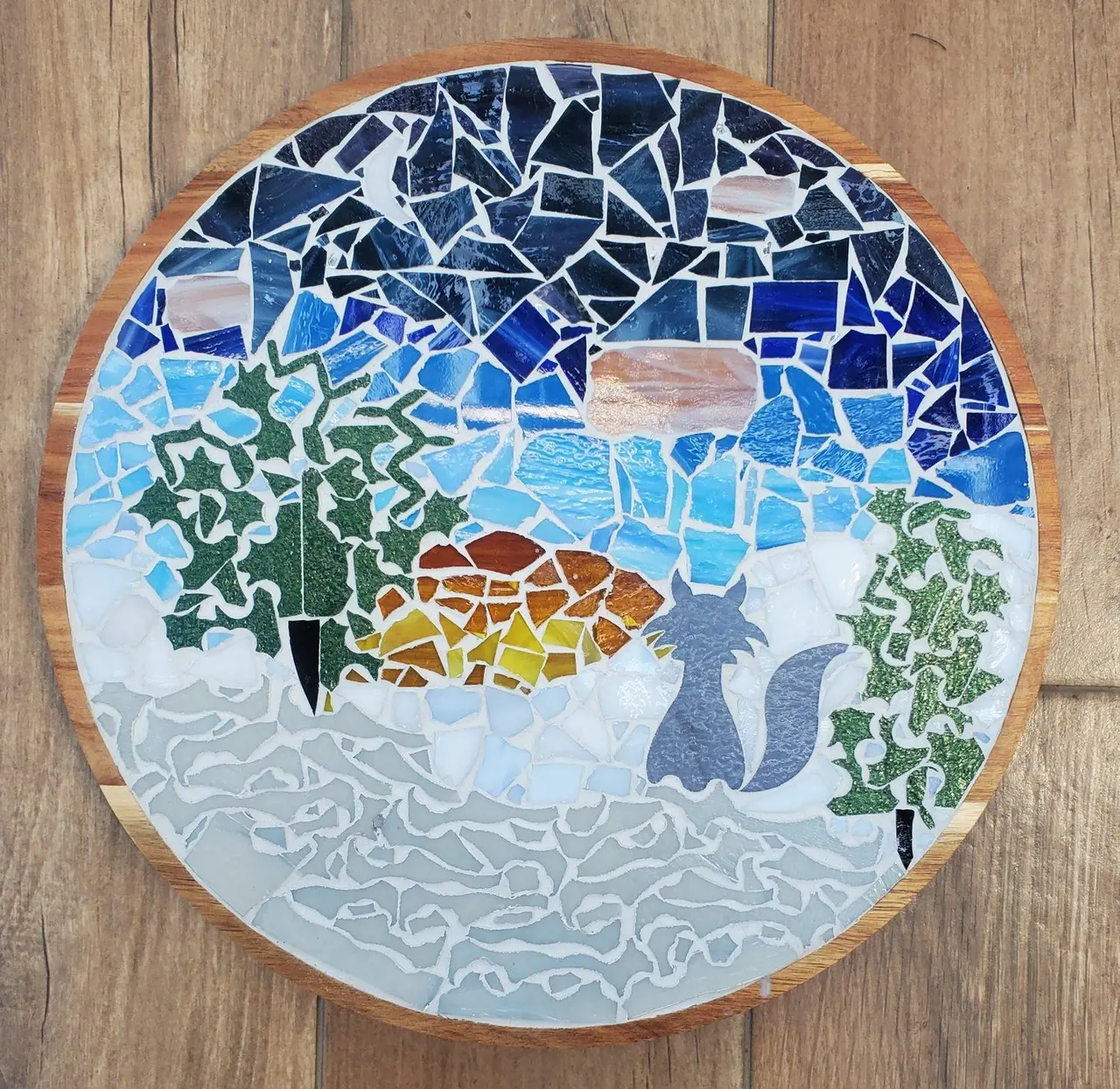 A round mosaic of a fox in a snowy forest under a starry sky