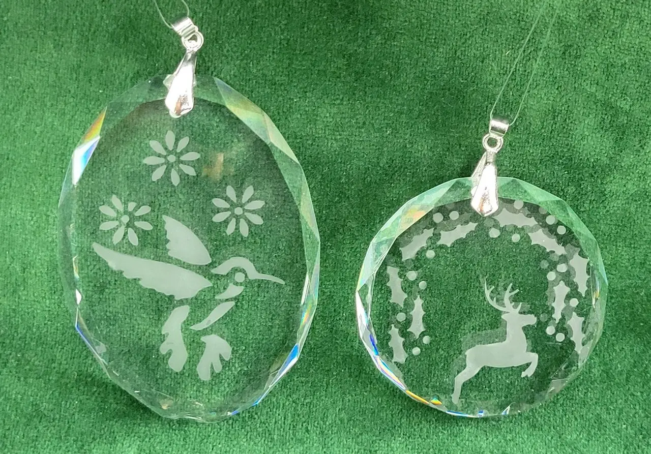 Two crystal ornaments etched with a hummingbird and a leaping deer