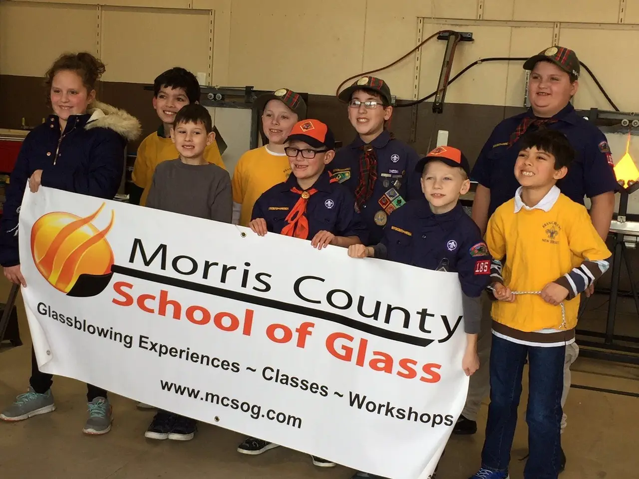 A Cub Scout pack holds a Morris County School of Glass banner